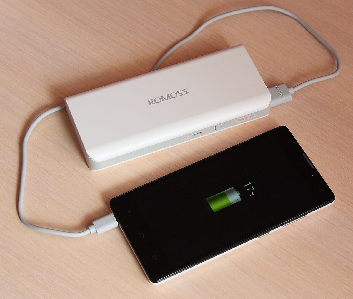 Power bank charging a phone on a desk