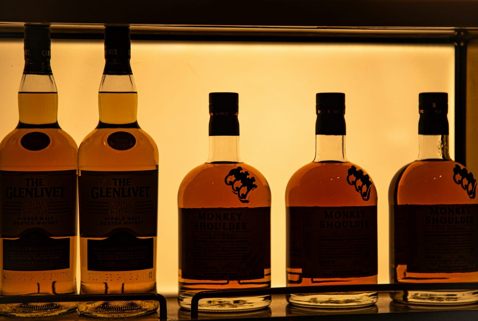 Whisky bottles lit on a bar shelf